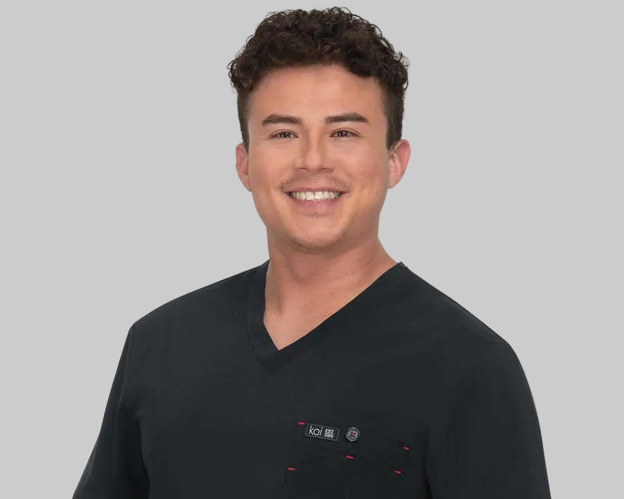 Man wearing a black scrub top with a rainbow detail on a white background